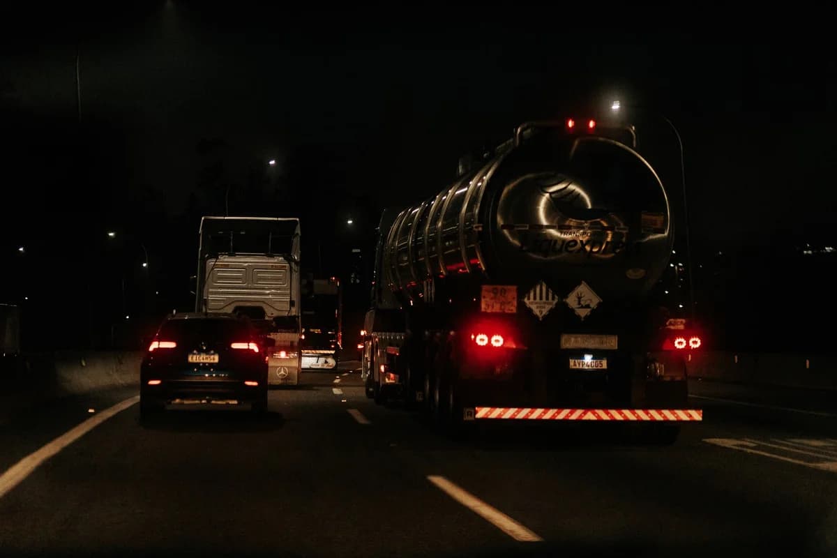Cars and trucks driving on a dark highway at night.