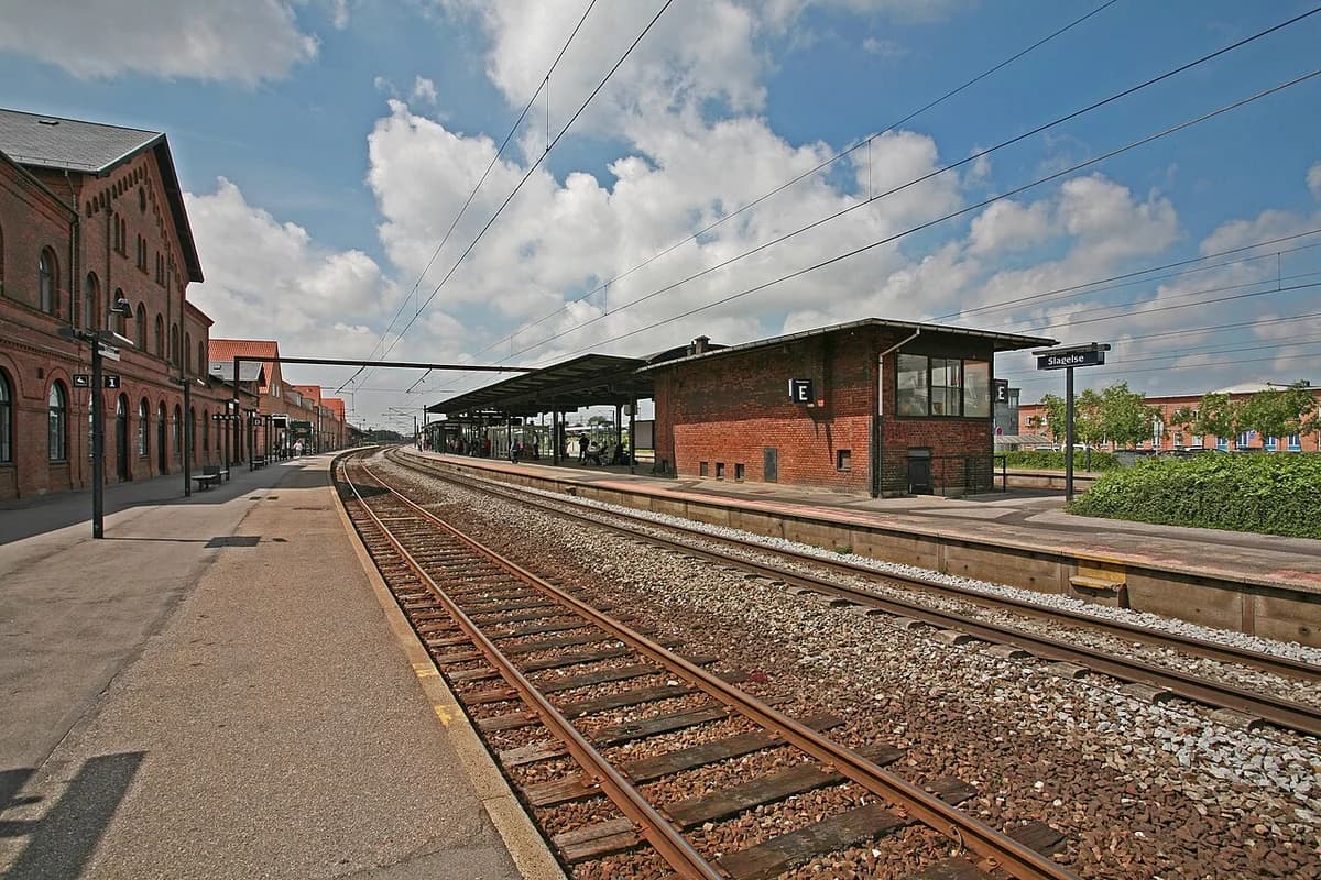 Platform view at Slagelse Station with tracks and station buildings.