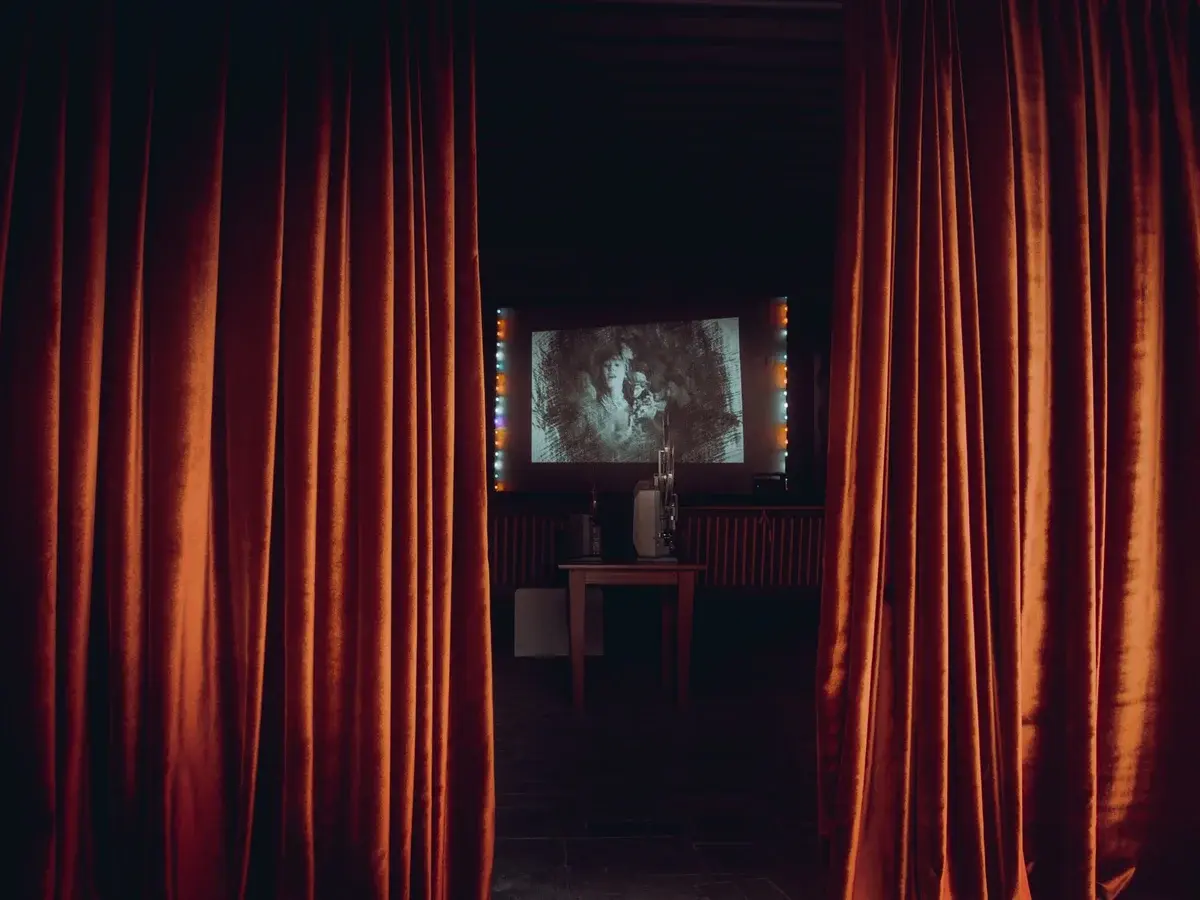A small movie theater with red curtains and a projector.