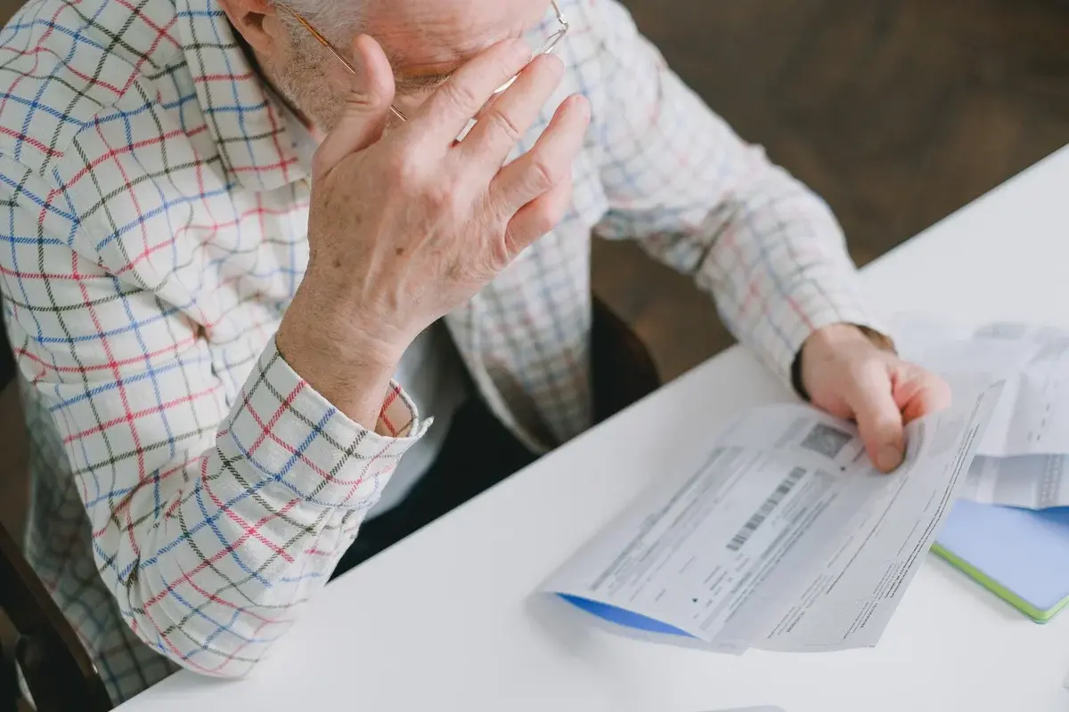 Elderly man looking over bills at a table