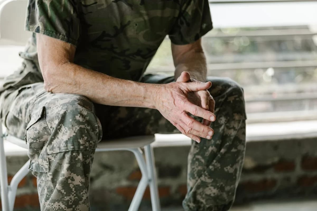 Man in military camouflage sitting with clasped hands