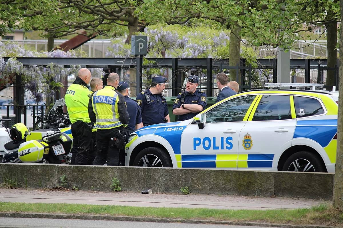 Swedish and Danish police officers standing together near police vehicles
