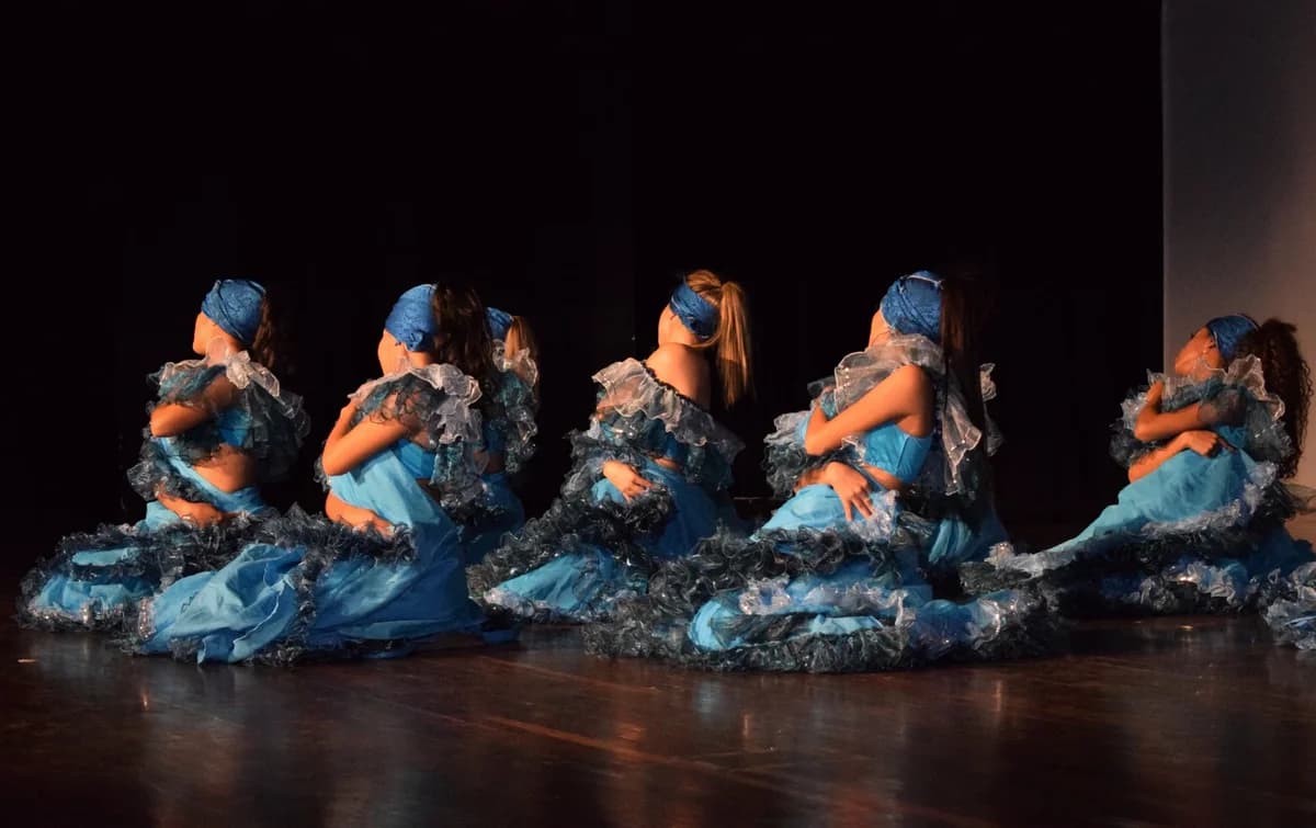 A group of dancers in blue costumes performing on stage.