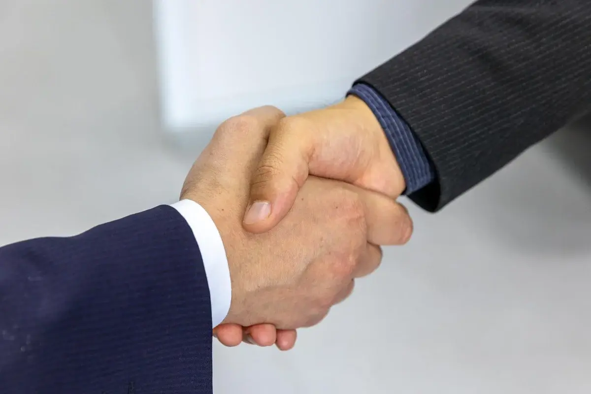 Two businessmen shaking hands in a professional setting.