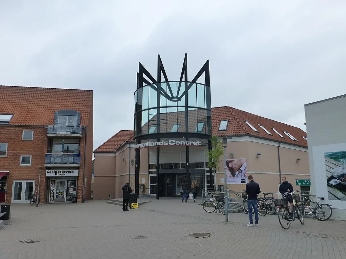 Entrance to a shopping center with bicycles and a few people outside.