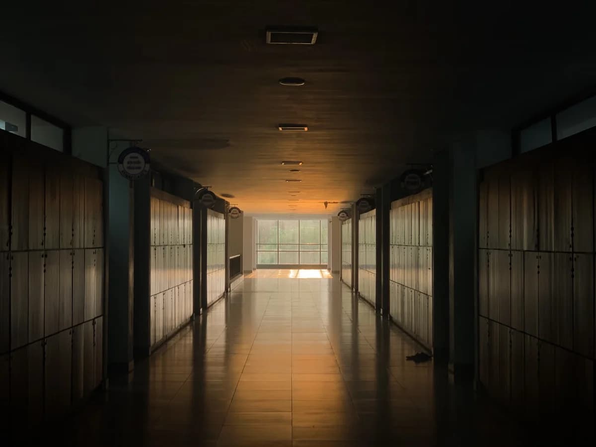 Empty school hallway with lockers and warm sunset light coming through a window.