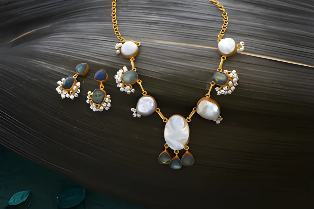 Pearl and gemstone necklace with matching earrings on dark textured surface