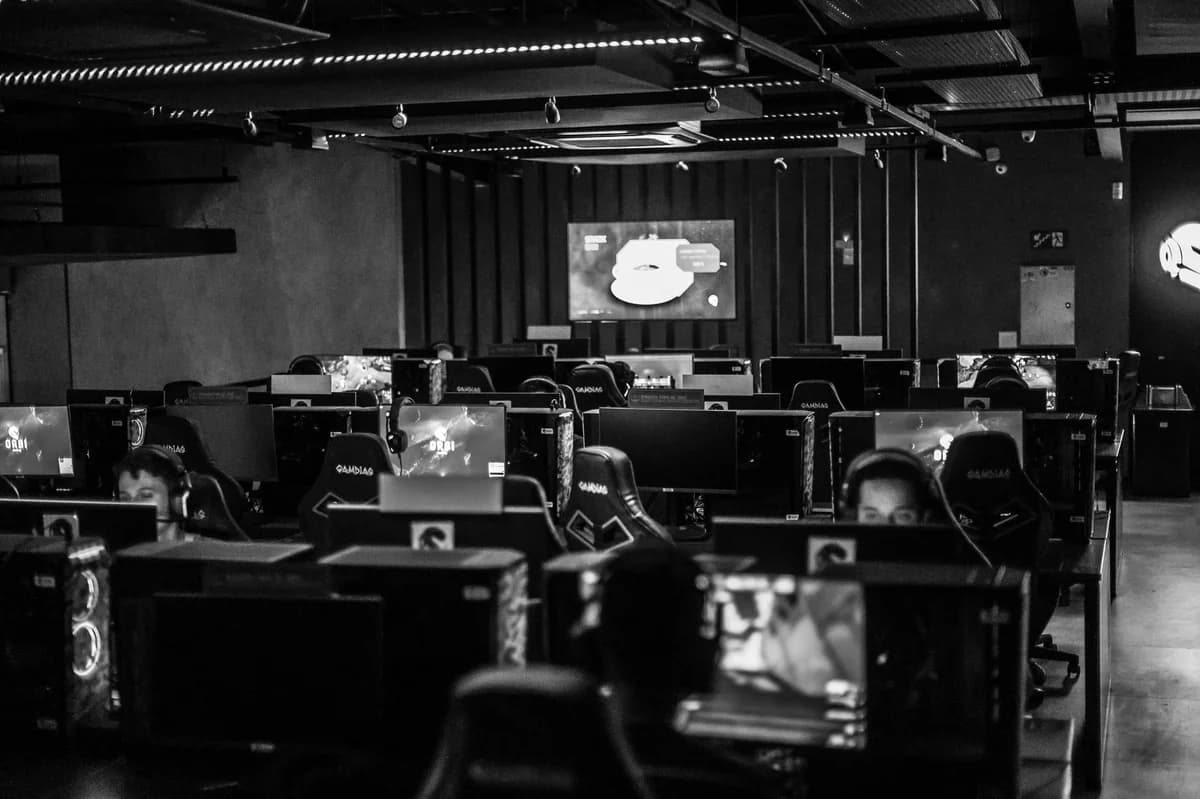 Black-and-white esports studio with players at computer stations.