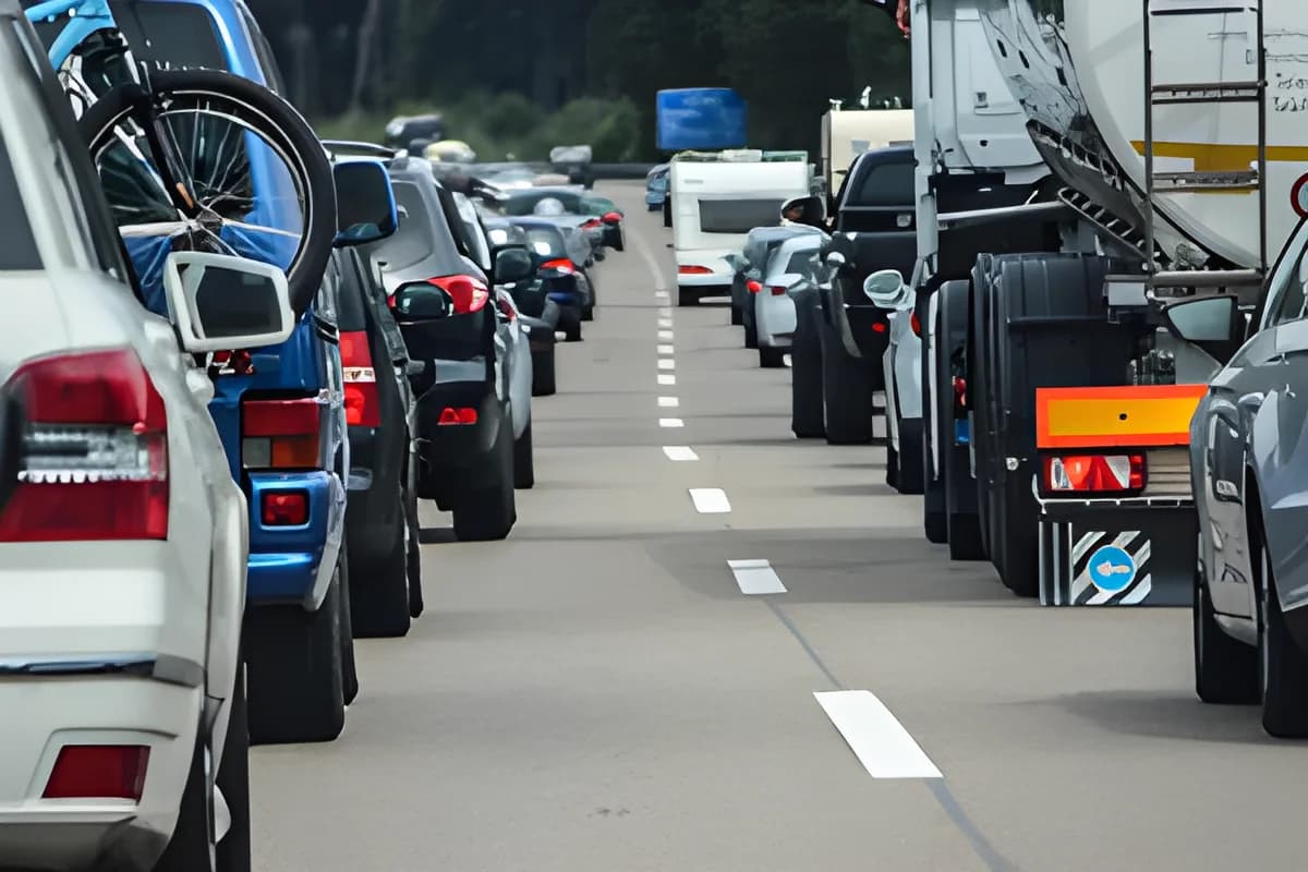 Cars and trucks stuck in heavy highway traffic with brake lights on.