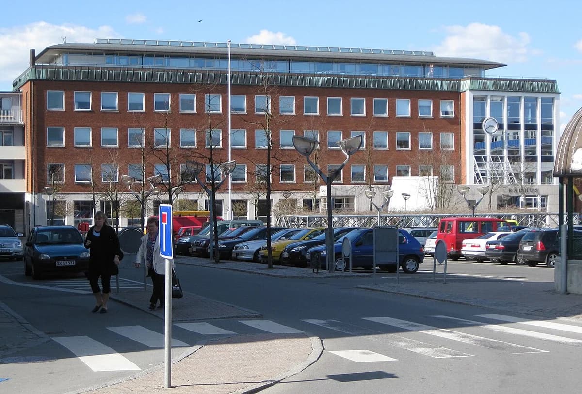 Slagelse Town Hall building with parked cars and pedestrians in front