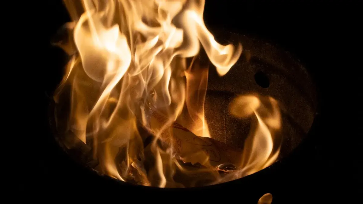 Bright flames rising from a metal container in darkness.