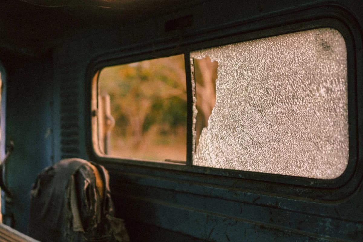 A shattered window inside an old abandoned vehicle.