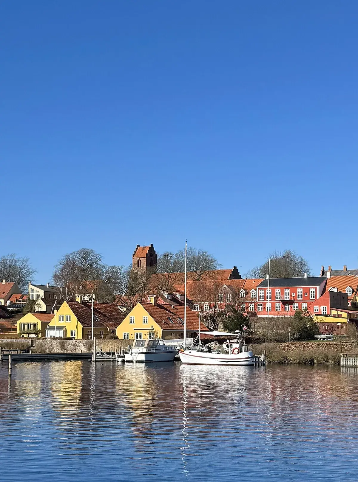 Waterfront view of colorful houses and boats in Skælskør, Denmark.