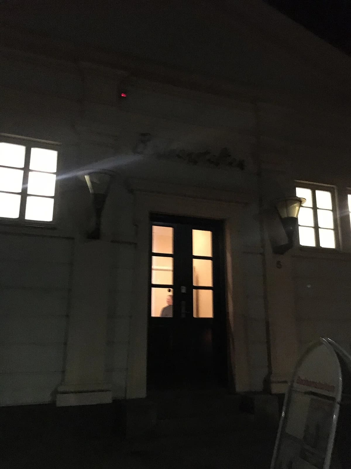 Nighttime exterior of a building with illuminated windows and a doorway.