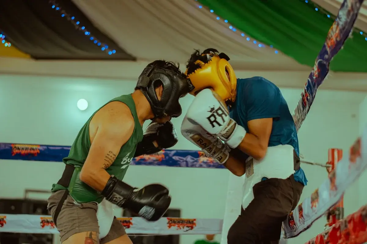 Two boxers sparring in a ring while wearing headgear and gloves.