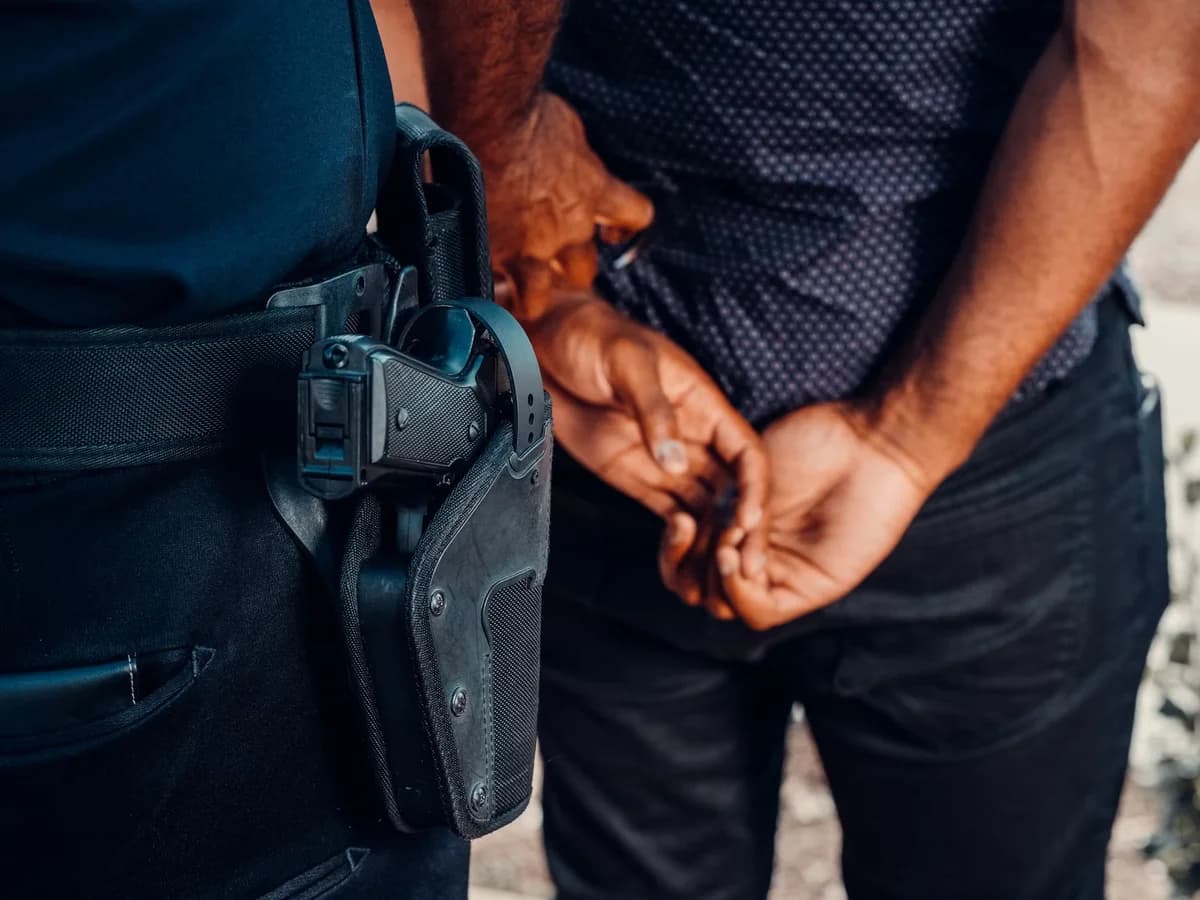 Police officer with holstered gun arresting suspect