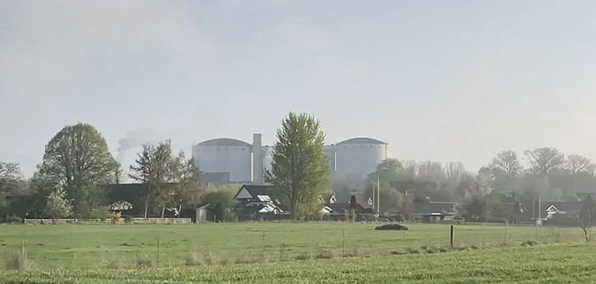 A sugar factory complex behind fields and houses in a rural area.